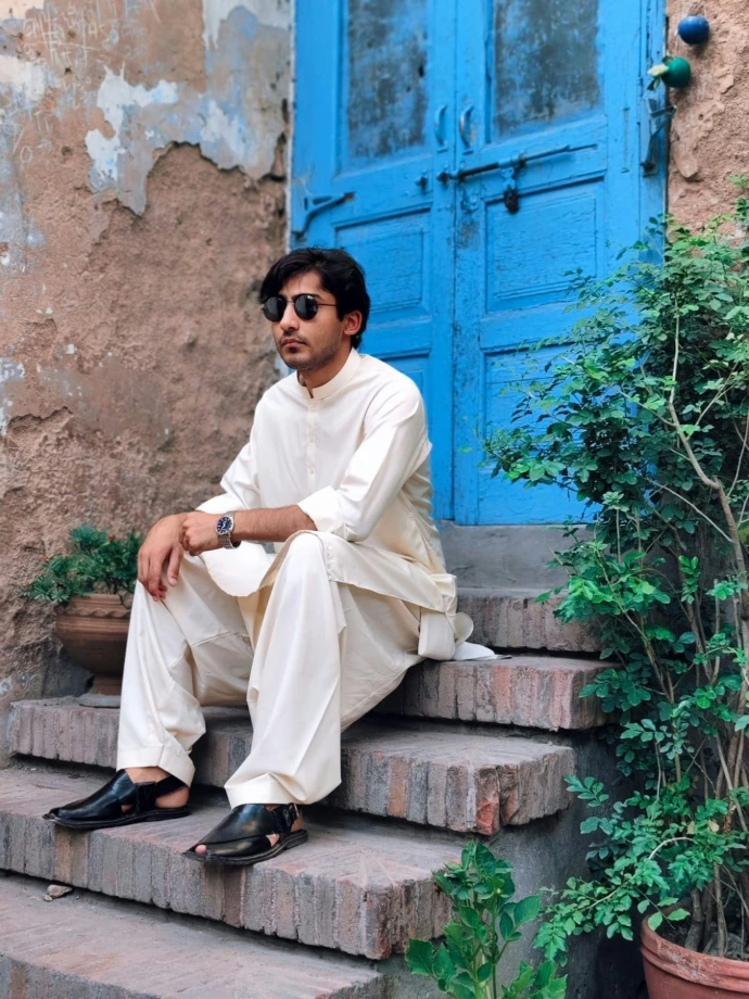 A man sitting on steps in front of a blue door
